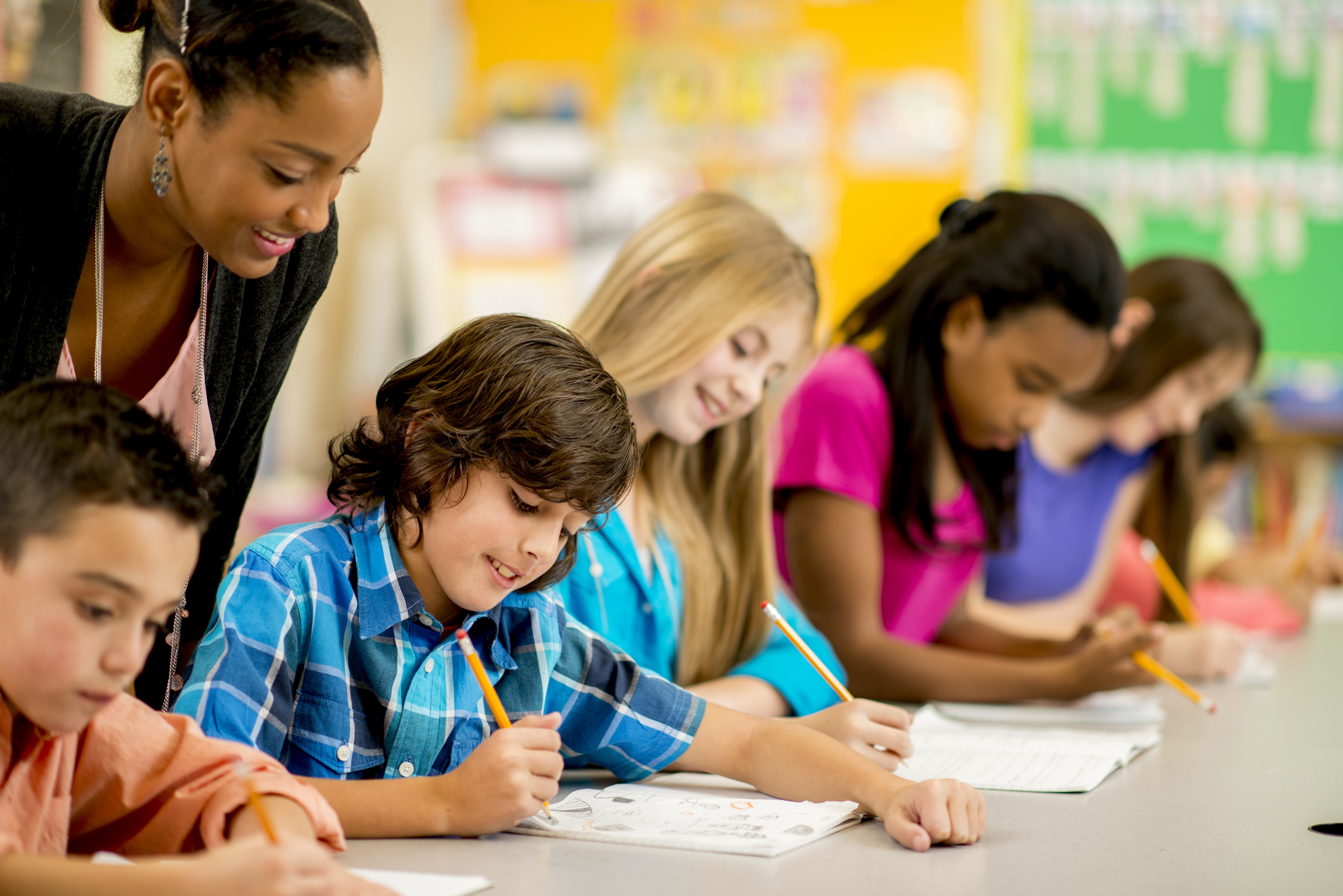 students writing with teacher oversight