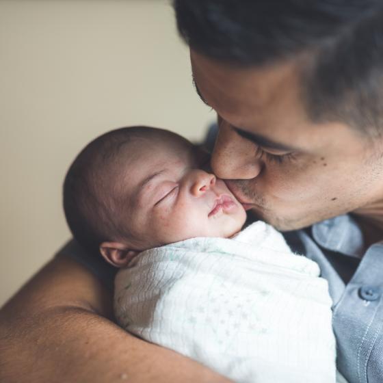father kissing newborn